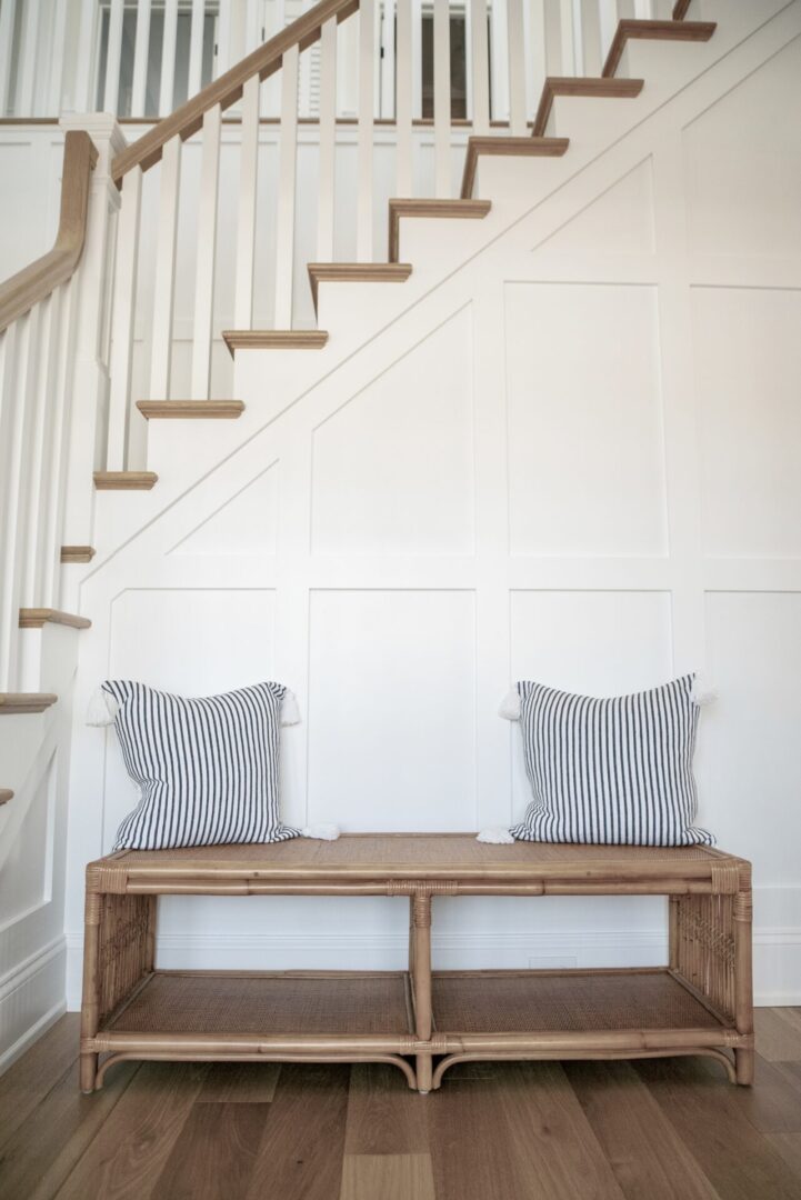 An ottoman chair with pillows at the base of the stairs