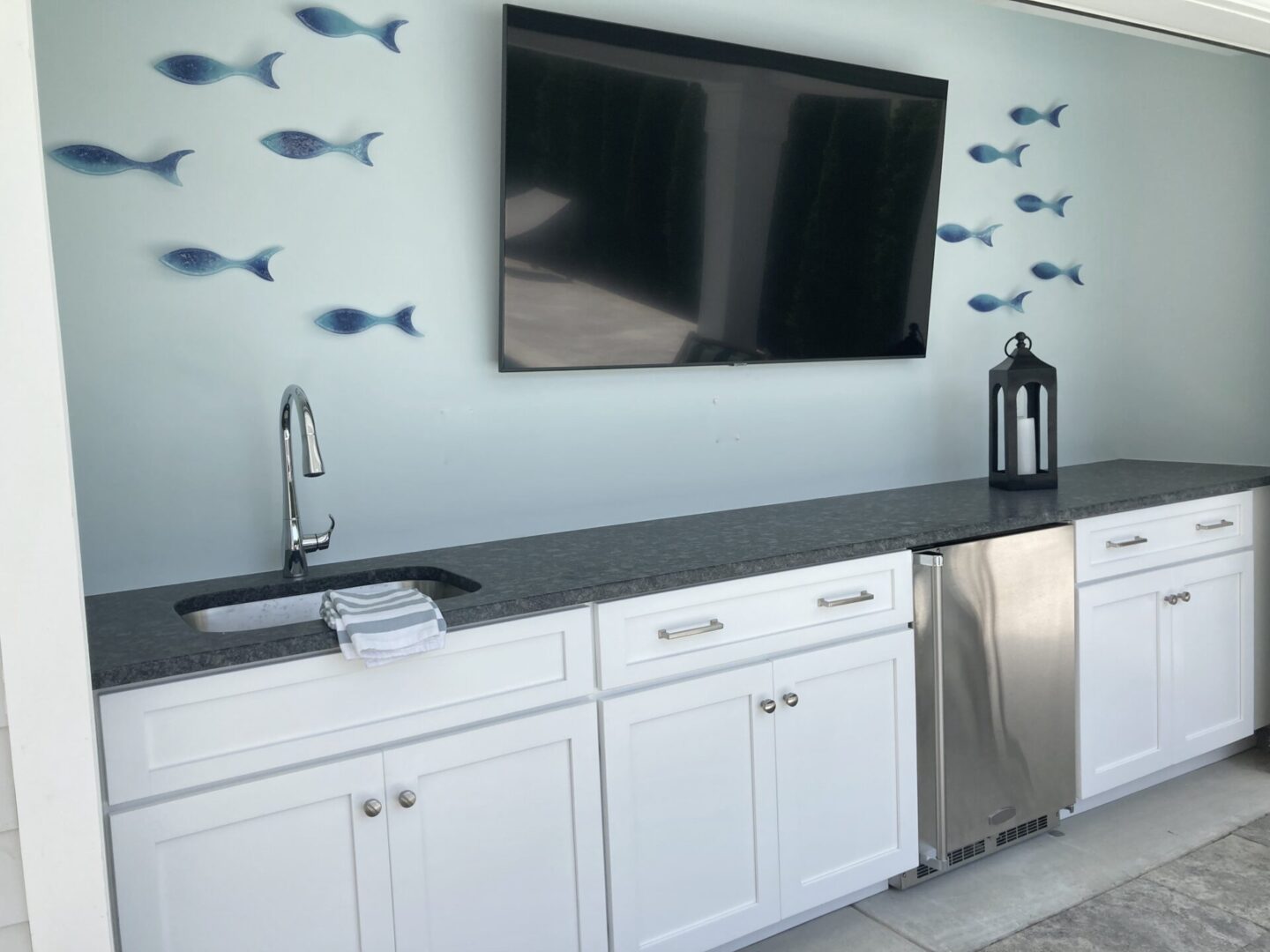 A sink and TV with cabinetry and countertops